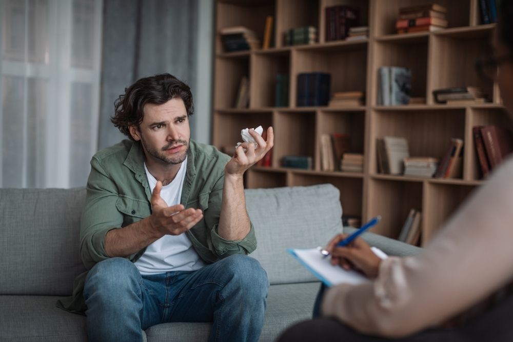 Recovery Mountain - Addressing the Seriousness of Cocaine Addiction. A man sits in a therapy office frustratedly speaking to a therapist taking notes.